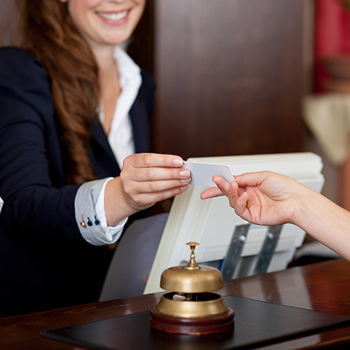 smiling female receptionist passing hotel room key card